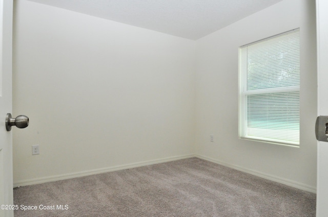 carpeted spare room featuring baseboards