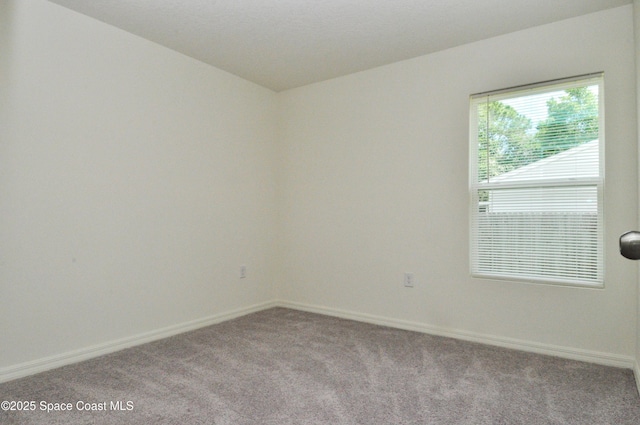 carpeted spare room featuring baseboards