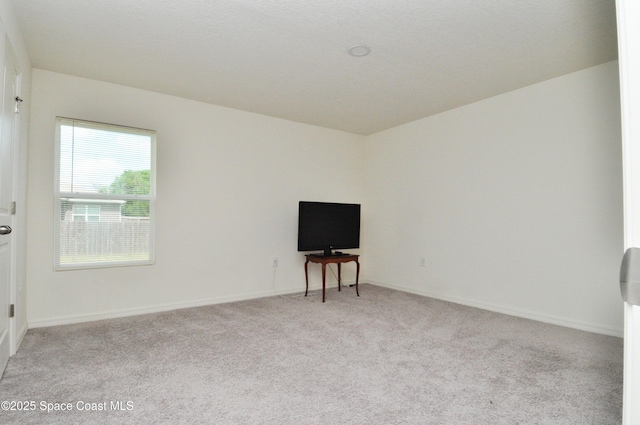 empty room featuring light carpet and baseboards