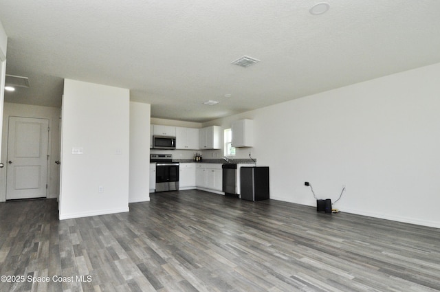 kitchen featuring open floor plan, dark wood-style flooring, white cabinetry, and appliances with stainless steel finishes
