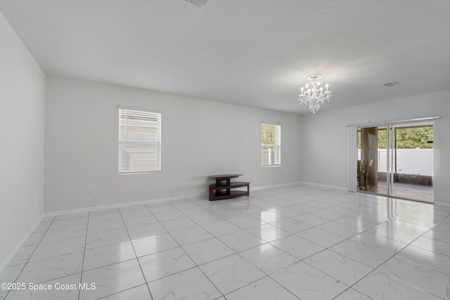 spare room with a textured ceiling and a chandelier