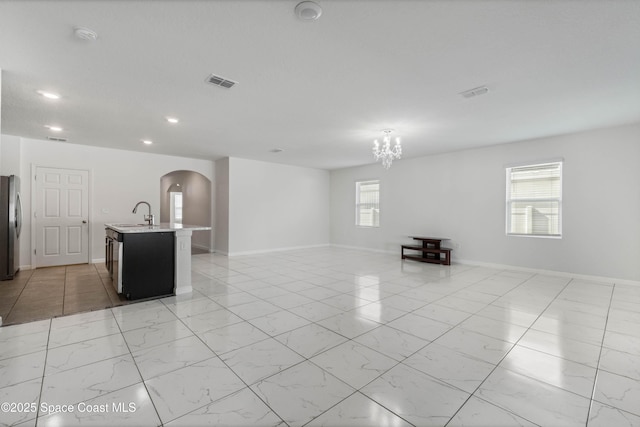 unfurnished living room featuring plenty of natural light and a chandelier