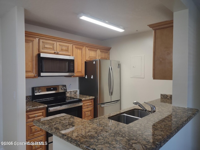 kitchen featuring appliances with stainless steel finishes, kitchen peninsula, sink, and dark stone countertops