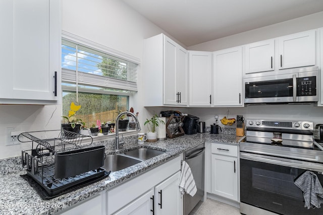 kitchen featuring sink, stainless steel appliances, white cabinets, and light stone countertops