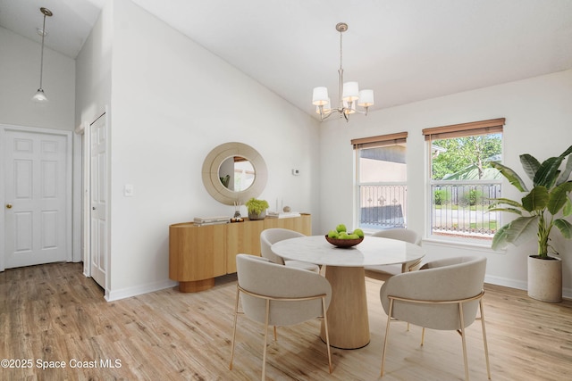 dining area featuring baseboards, light wood-type flooring, high vaulted ceiling, and a notable chandelier