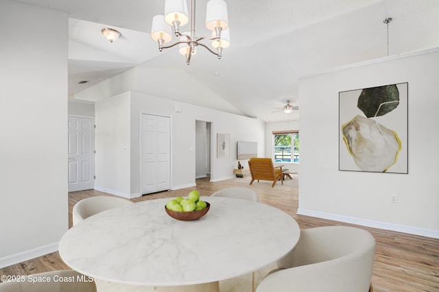 dining room with light wood finished floors, ceiling fan with notable chandelier, baseboards, and lofted ceiling