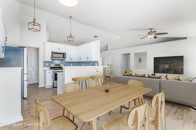 dining area with visible vents, ceiling fan, light wood-type flooring, and lofted ceiling