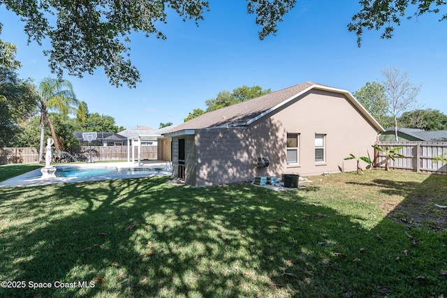 rear view of property featuring a fenced backyard, a lawn, and stucco siding