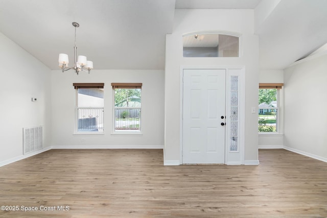 foyer entrance featuring a notable chandelier, visible vents, baseboards, and wood finished floors