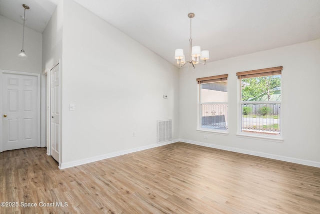 unfurnished room featuring baseboards, an inviting chandelier, light wood-style floors, visible vents, and high vaulted ceiling