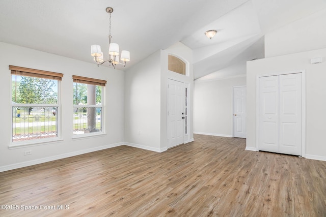 unfurnished room with baseboards, light wood-type flooring, vaulted ceiling, and an inviting chandelier