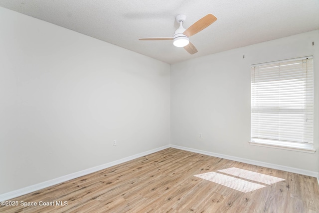 spare room featuring ceiling fan, light wood finished floors, and baseboards