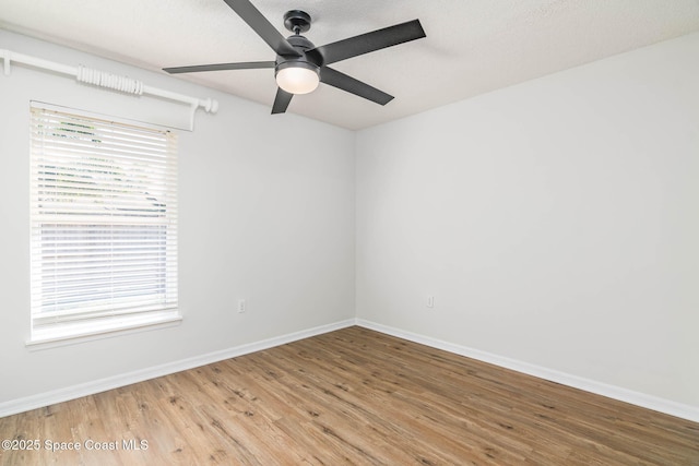 empty room featuring baseboards, a ceiling fan, wood finished floors, and a textured ceiling