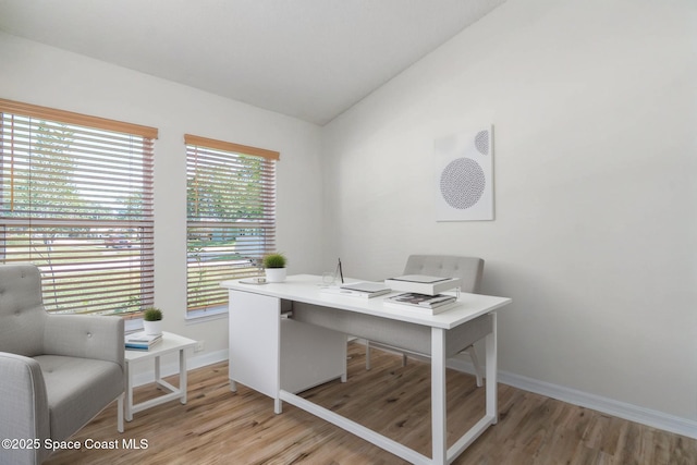 office area featuring baseboards, light wood-style floors, and vaulted ceiling