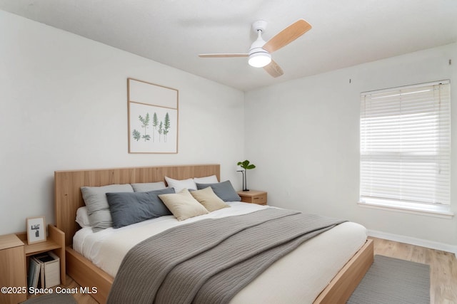 bedroom featuring baseboards, light wood-type flooring, and a ceiling fan