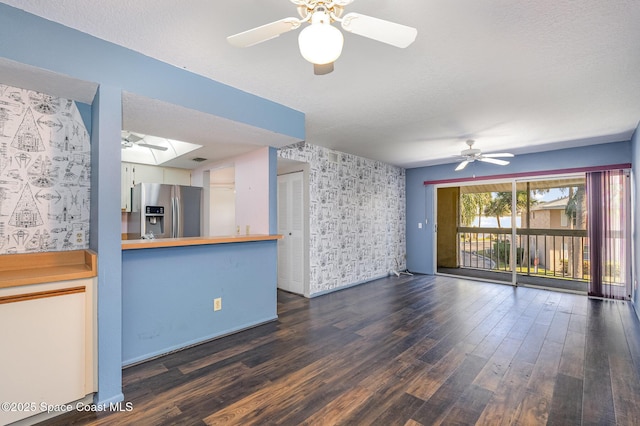 unfurnished living room featuring dark wood-type flooring, ceiling fan, and a skylight