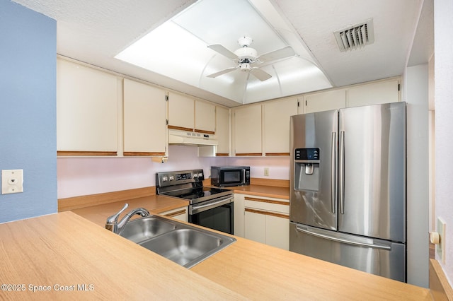 kitchen with ceiling fan, appliances with stainless steel finishes, sink, and cream cabinetry