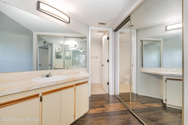 bathroom featuring vanity, a textured ceiling, wood-type flooring, and toilet