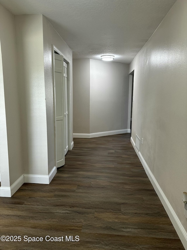 hall featuring dark wood-type flooring and a textured ceiling