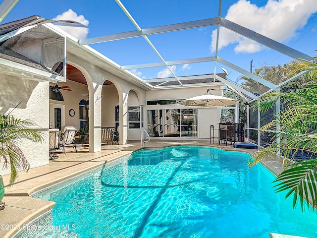 view of swimming pool featuring ceiling fan, a lanai, and a patio area