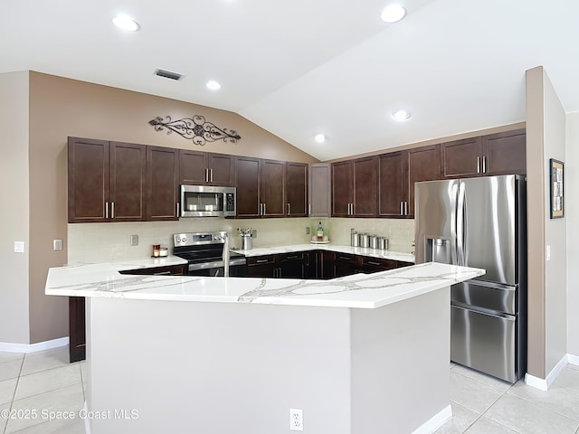 kitchen with lofted ceiling, light tile patterned floors, appliances with stainless steel finishes, backsplash, and dark brown cabinetry