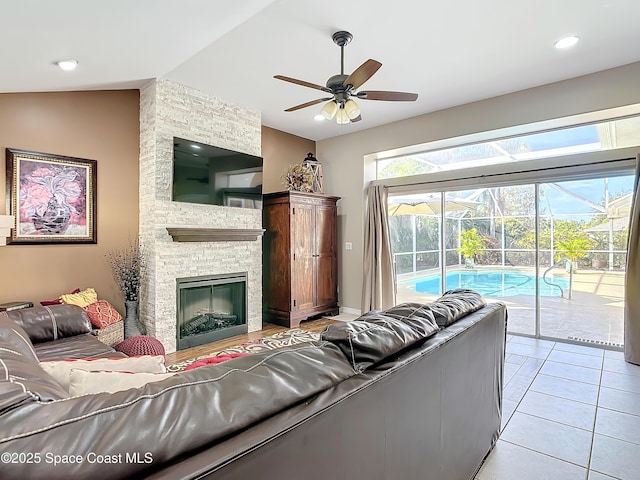 living room with lofted ceiling, light tile patterned floors, a fireplace, and ceiling fan