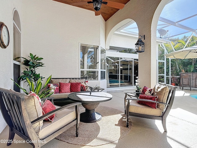 view of patio / terrace with ceiling fan, an outdoor hangout area, and glass enclosure