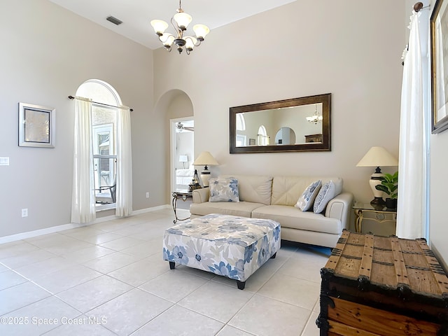 tiled living room with ceiling fan with notable chandelier