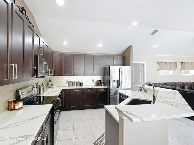 kitchen featuring stainless steel appliances, an island with sink, sink, and light tile patterned floors