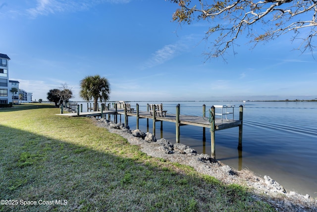 view of dock with a water view and a lawn