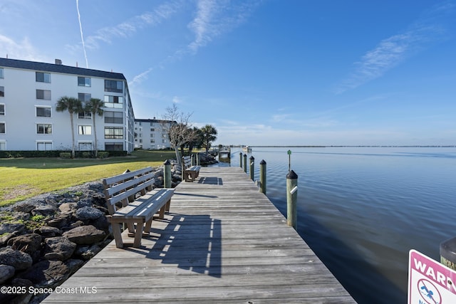 dock area with a lawn and a water view