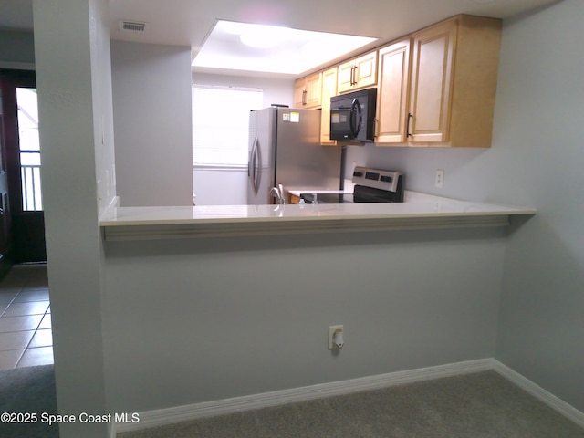 kitchen with stainless steel fridge, electric range oven, and light brown cabinets