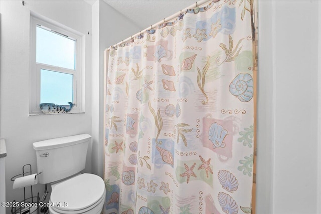 bathroom featuring curtained shower and toilet