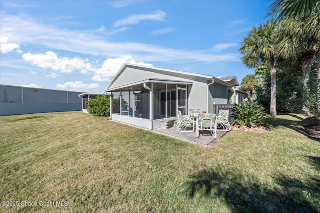 rear view of house featuring a lawn, a sunroom, and a patio