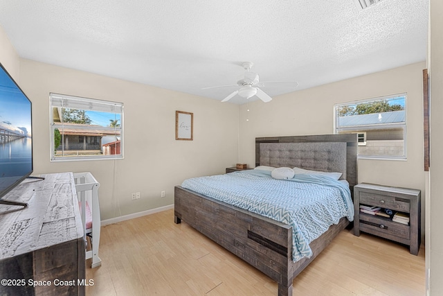 bedroom with ceiling fan, a textured ceiling, and light wood-type flooring