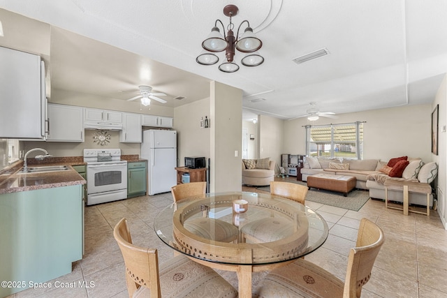 dining area with sink, ceiling fan with notable chandelier, and light tile patterned floors