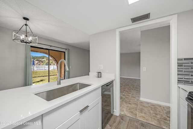 kitchen featuring white cabinetry, dishwasher, sink, hanging light fixtures, and an inviting chandelier