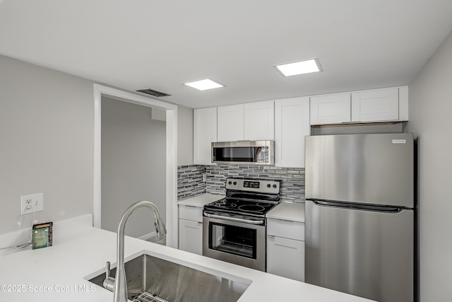 kitchen featuring stainless steel appliances, sink, decorative backsplash, and white cabinets