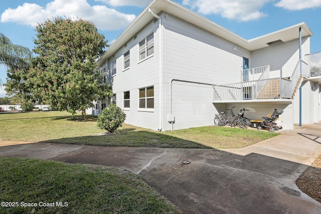 view of property exterior with a balcony and a lawn