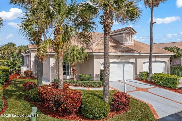 view of front facade featuring a garage, a tiled roof, concrete driveway, and stucco siding