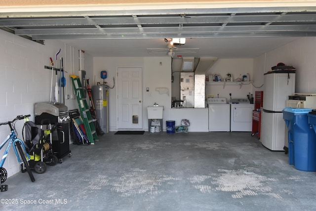 garage featuring washing machine and clothes dryer, a garage door opener, and water heater