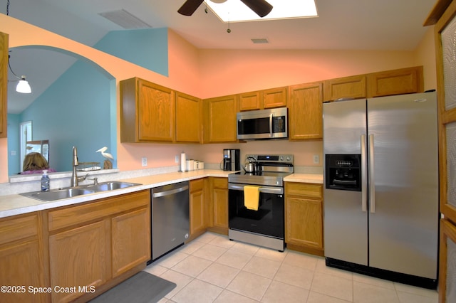 kitchen featuring sink, vaulted ceiling, light tile patterned floors, appliances with stainless steel finishes, and ceiling fan