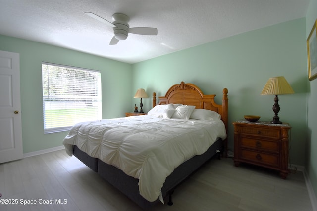 bedroom with ceiling fan, light hardwood / wood-style flooring, and a textured ceiling