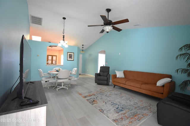 living room with ceiling fan with notable chandelier, wood-type flooring, and high vaulted ceiling