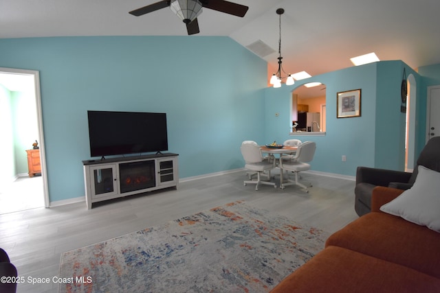 living room with lofted ceiling, ceiling fan with notable chandelier, and light hardwood / wood-style floors