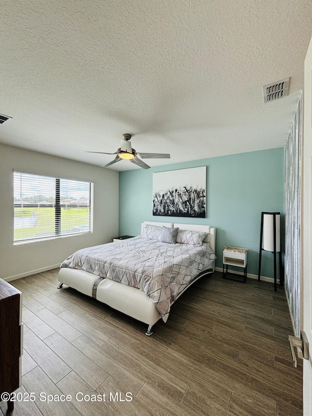 bedroom with hardwood / wood-style flooring, a textured ceiling, and ceiling fan