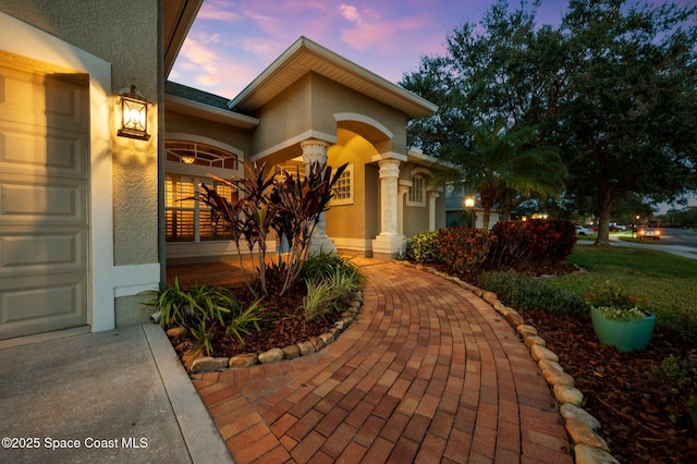 exterior entry at dusk featuring a garage