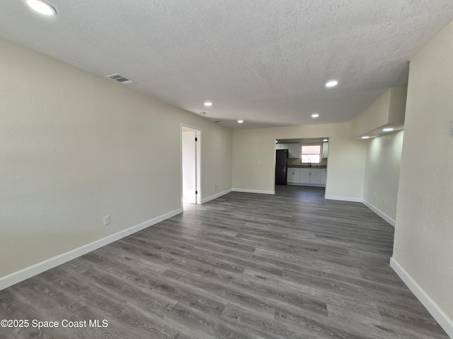 unfurnished living room featuring dark wood-type flooring and a textured ceiling