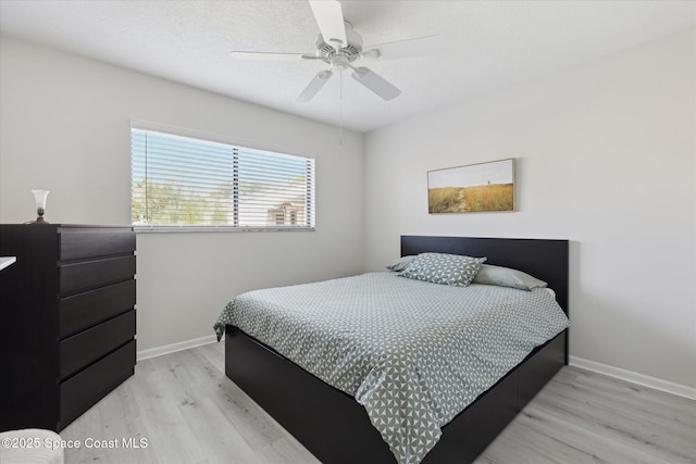 bedroom with ceiling fan, light hardwood / wood-style floors, and a textured ceiling