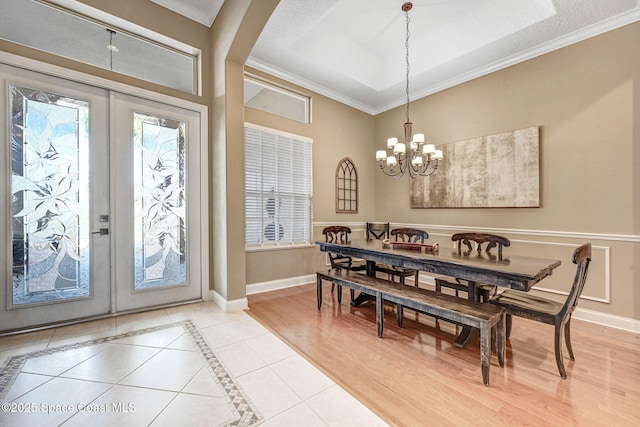 tiled dining area featuring crown molding, an inviting chandelier, and french doors